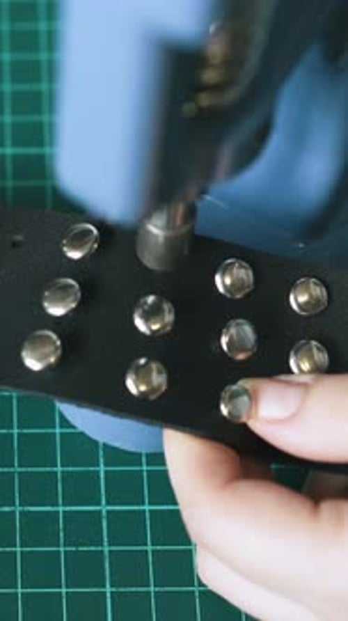 Craftsperson Attaching Metal Rivets to Black Material