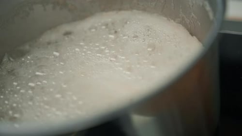 Petit déjeuner sain, casserole en acier inoxydable, louche remplie de porridge avec des flocons d'avoine bouillants sur la cuisinière