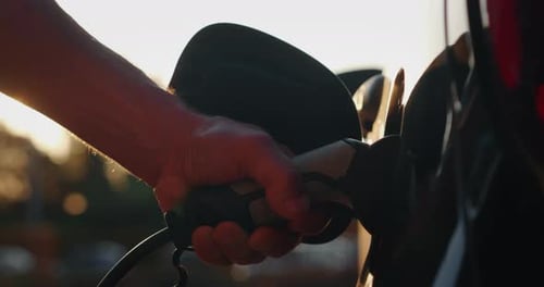 Slow motion close up of power supply plugged into an electric car for charging a modern battery wh