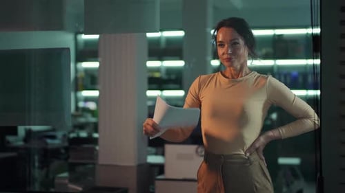 A Focused and Driven Woman in a Sleek Modern Office Setting Confidently Holding a Document While