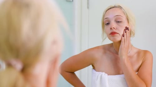 Young Woman Looks in Mirror After Shower