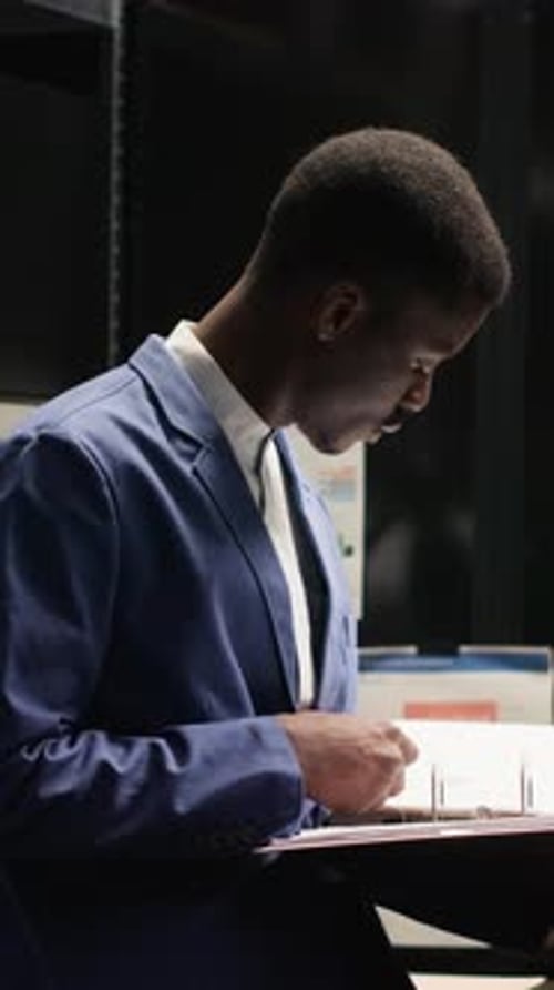 Young Adult Man Reviewing Binder in Office