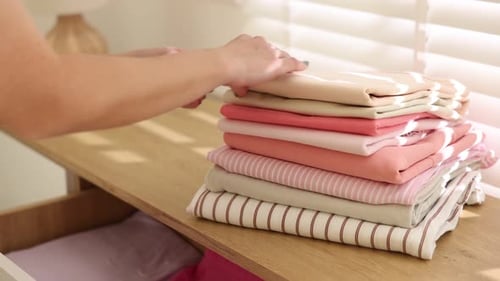 Woman putting clothes into drawer of cabinet indoors, closeup