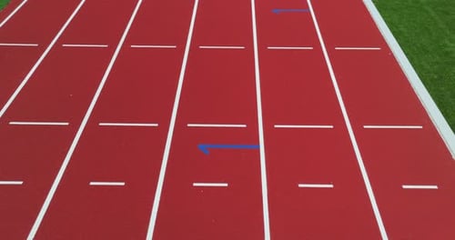 Track Lane Numbers on a Red Athletic Field During a Lighted Event