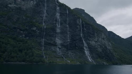 The Seven Sisters waterfall cascades down the cliffs into the serene Geiranger Fjord in Norway