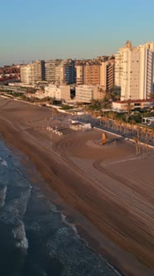 Aerial drone view of the Mediterranean Sea and the city of Alicante, Spain at sunset. Vertical