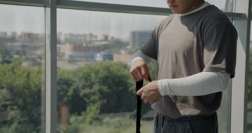 Male MMA Fighter Getting Ready for Training Wrapping Hands with Protective Straps Wearing Trendy