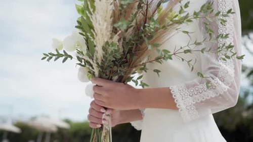 Bride Holding Wedding Bouquet near the Ocean