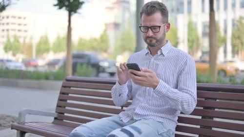 Man Using Cell Phone on Park Bench