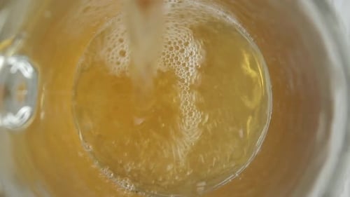 Amber Liquid Pouring Into a Clear Glass
