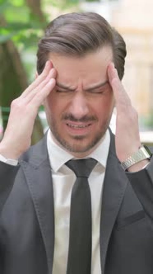 Man in Suit Massaging Temples with Fingers