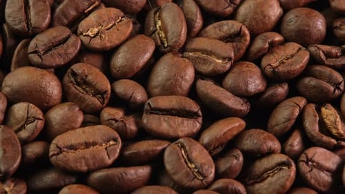 Roasted coffee beans rotating as background close-up macro top view. Concept for coffee shop