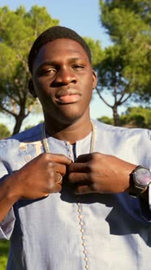 Young Senegalese Man Adjusting Traditional Dashiki in Park