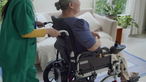 Nurse Assists Senior Woman in Wheelchair at Home