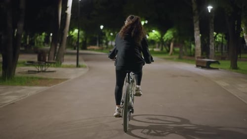 Relaxed Female Cyclist Traversing Tranquil Forest Pathway At Dusk Serene Woman Enjoying Peaceful