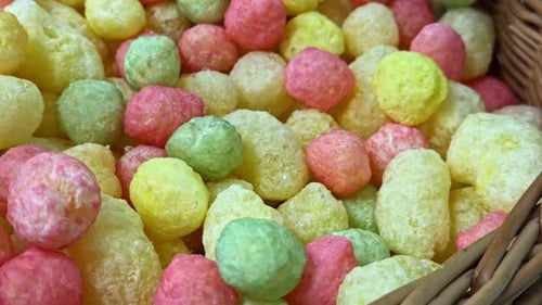 Nahaufnahme bunter Puffsnacks in Rosa-, Gelb- und Grüntönen