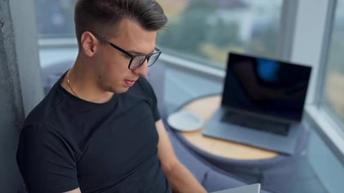 Busy man writing in paper book. Young businessman working in a cozy space. High angle view
