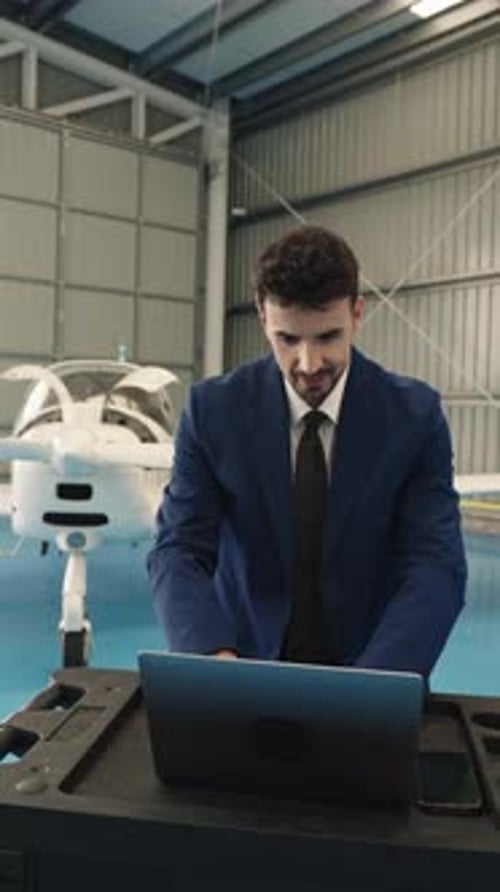 Empresario analizando datos de computadoras portátiles en un entorno de hangar de aviones