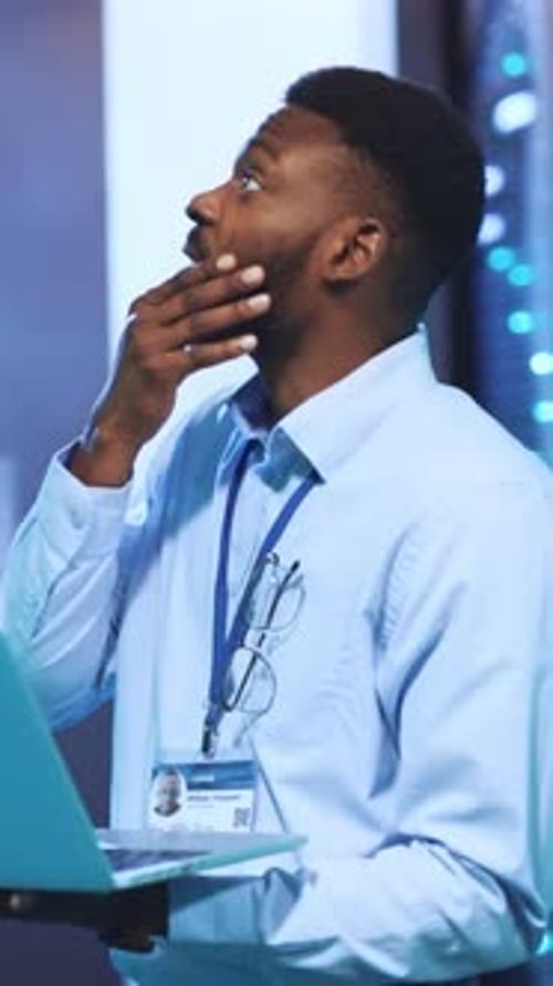 Man Working in Server Room Typing on Laptop