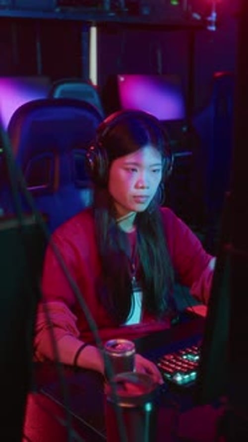 Asian Girl Playing Online Video Game in Cyberclub and Sipping Energy Drink