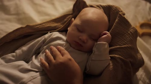 Hand of Woman Caressing Newborn Boy Sleeping in Baby Cocoon