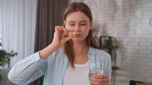 Woman Drinks Water While Taking Vitamin Supplement