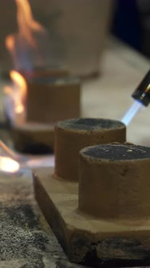 Foundry Worker Using Blowtorch on Small Clay Cylinders Stock Clip