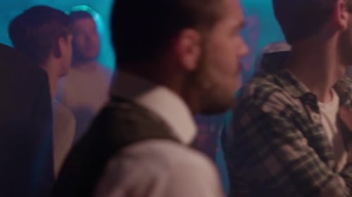 Männer tanzen energisch in einem lebhaften Club, umgeben von Nachtschwärmern