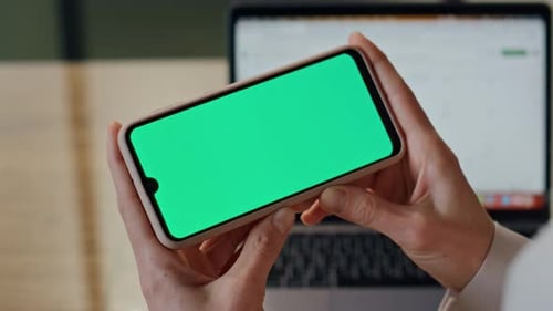 Woman Holding Smartphone with Green Screen in Office