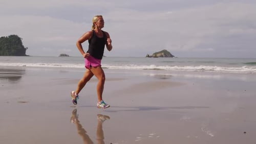 Young woman jogging carefree on a sunny beach in tropical costa rica in slow motion