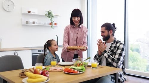 Smiling Family Enjoying Pizza at Home Together