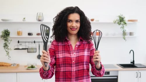 Woman Holding Spatula and Whisk in Bright Kitchen