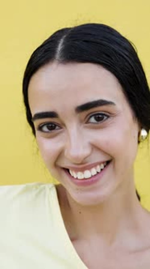 Smiling young woman in front of yellow background
