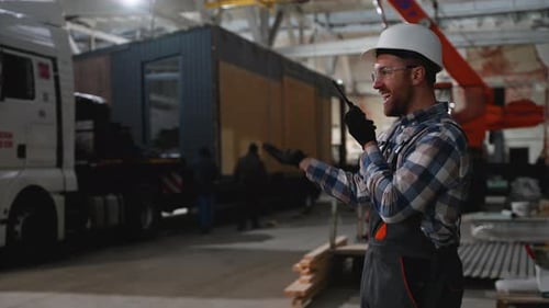 Worker Giving Instructions Via Radio During Prefab Home Loading