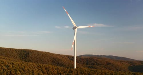 Aerial close up shot of wind mills rotating by the force of the wind and generating renewable ener
