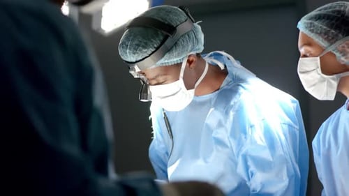 Diverse surgeons wearing surgical gowns operating on patient in operating theatre, slow motion