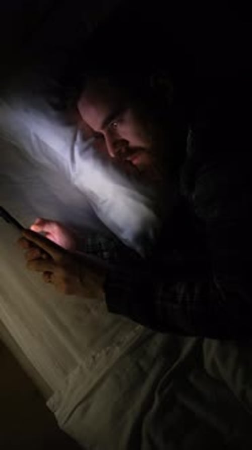 Young Guy Scrolling A Social Media Feed In Bed At Night