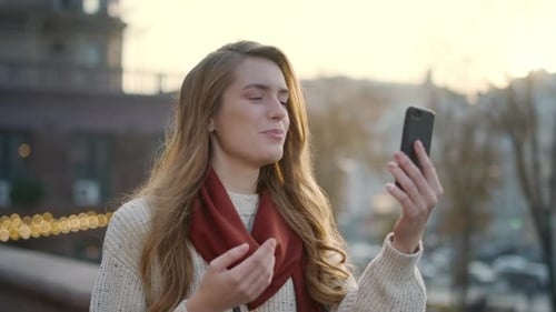 Smiling Woman Video Chatting on Phone Outdoors