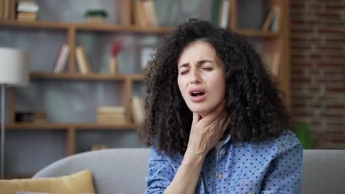 Woman Experiencing a Sore Throat Indoors During the Day