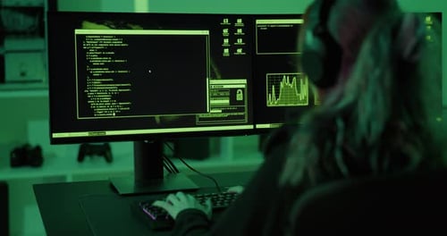 Person Coding at Computer in Dark Room