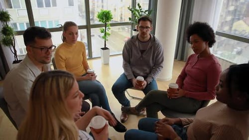 Diverse group of people sitting in circle in group therapy session.