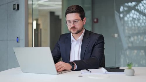 Confident Businessman Working On Laptop Smiling In Office