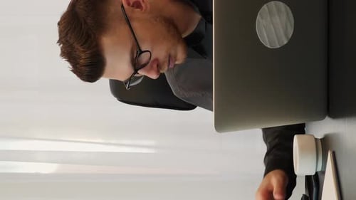 Man calculating earning at modern office, taking note in notebook.Vertical video
