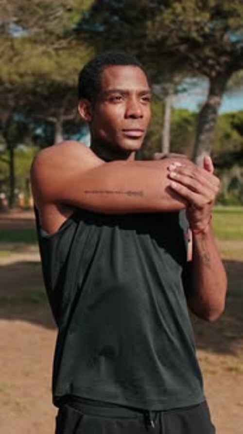 Vertical video, Young Man Stretching in Park Before Workout