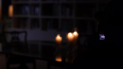 Close-up silhouette of a cameraman preforming a dolly shot in a dark room.
