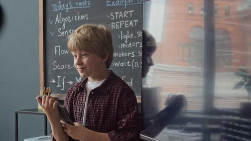 Schüler mit Tablet erklärt Robotikcode auf dem Bildschirm im Klassenzimmer