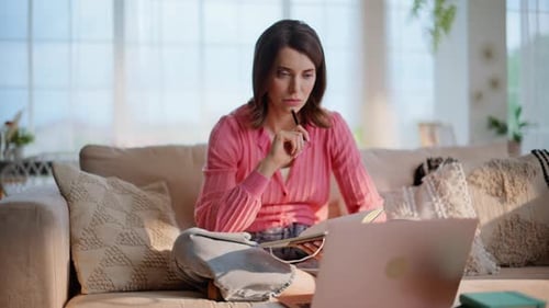 Woman Working from Home Taking Notes on Couch