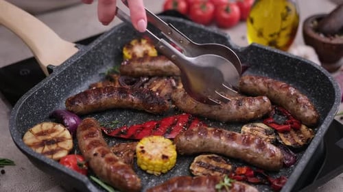Homemade Juicy Pork Sausages with Spices and Vegetables Frying on Grill Frying Pan