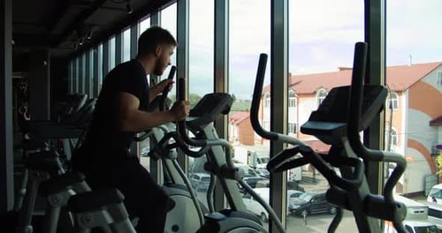 Athletic Man Uses Elliptical Machine at Gym