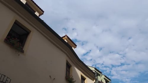 Low-angle shot of a charming building with flower boxes under a partly cloudy sky